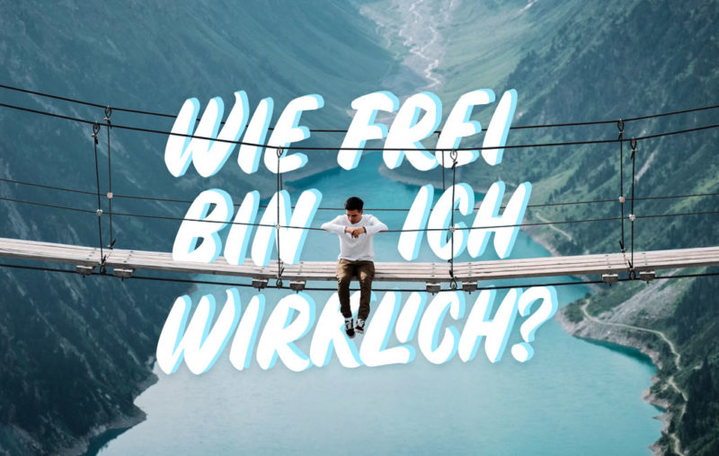 Mann sitzt auf einer Hängebrücke im Tal über einem See als Blogbild für Wie frei bin ich wirklich?